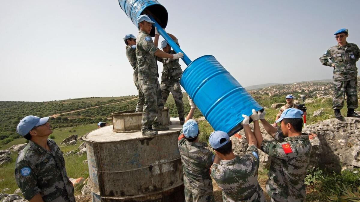 UN Peacekeepers lift equipment outdoors.